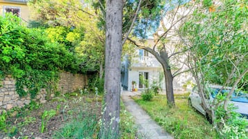 A stone wall, a pathway, and a building with a door and windows.