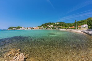 Eine Küstenstadt mit klarem Wasser, felsigem Strand und Gebäuden an einem Hügelhang.