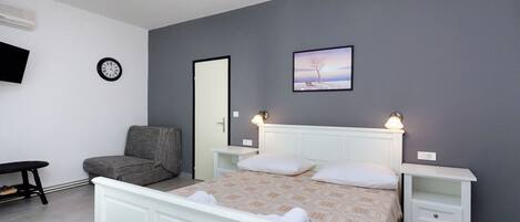 Un dormitorio con cama, mesitas de noche, una silla, un reloj y un cuadro en la pared.