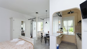 A compact hotel room with a bed, a small dining table, and a kitchenette. - Apartments Marija G (Rab)