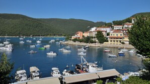 A marina with numerous boats docked, surrounded by hillside buildings and greenery. - Apartments Lory (Labin)