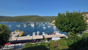 A marina with boats docked, surrounded by greenery and hills. - Apartments Lory (Labin)