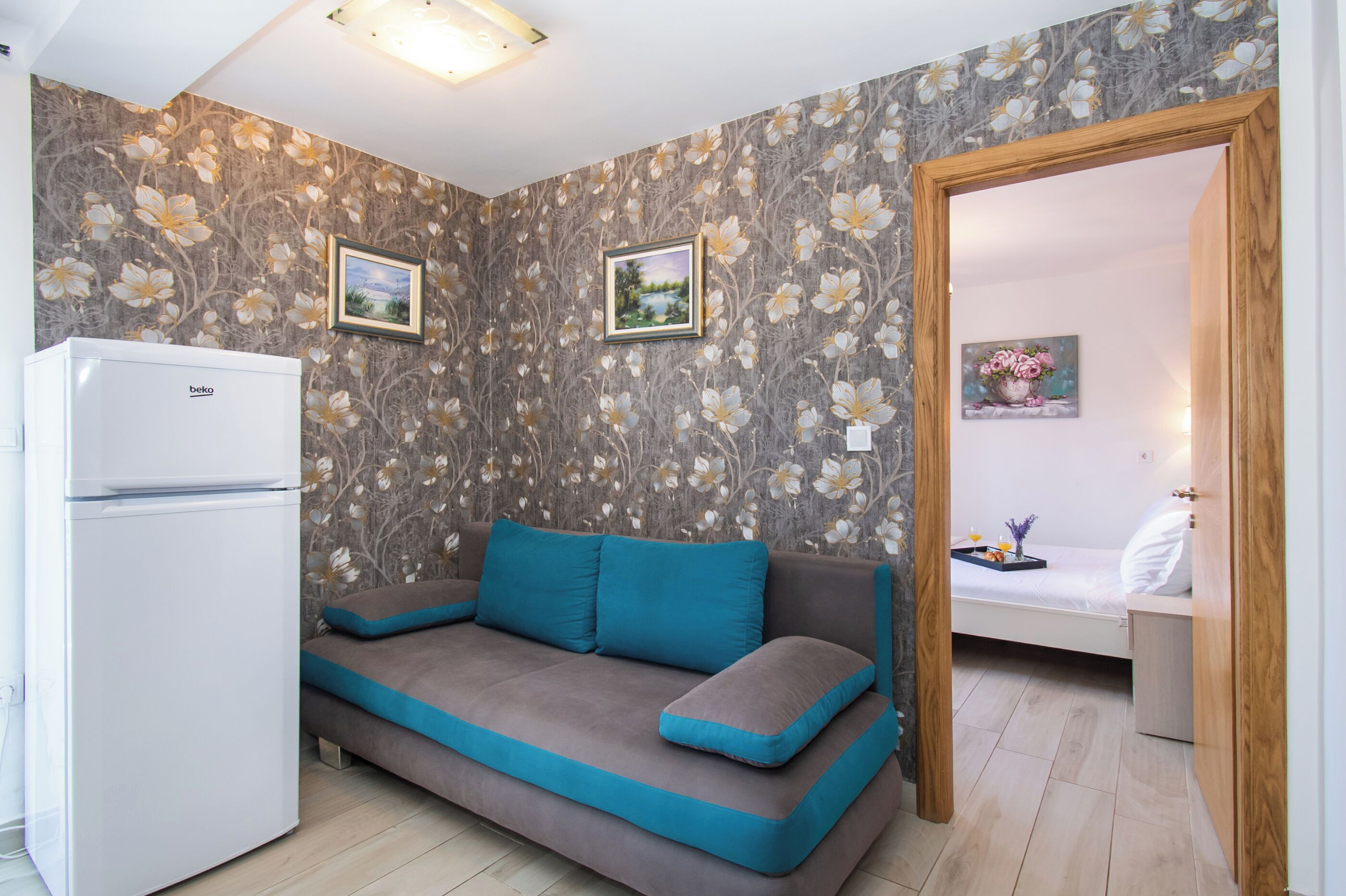 Ein kleiner Wohnraum mit einer Couch, einem Kühlschrank und einem Bett.