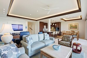 Un salon spacieux comprenant un canapé, des fauteuils, une table basse et un coin repas avec des chaises et une table.