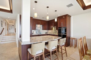 Una cocina moderna con una isla grande, armarios de madera oscura y encimera de mármol.