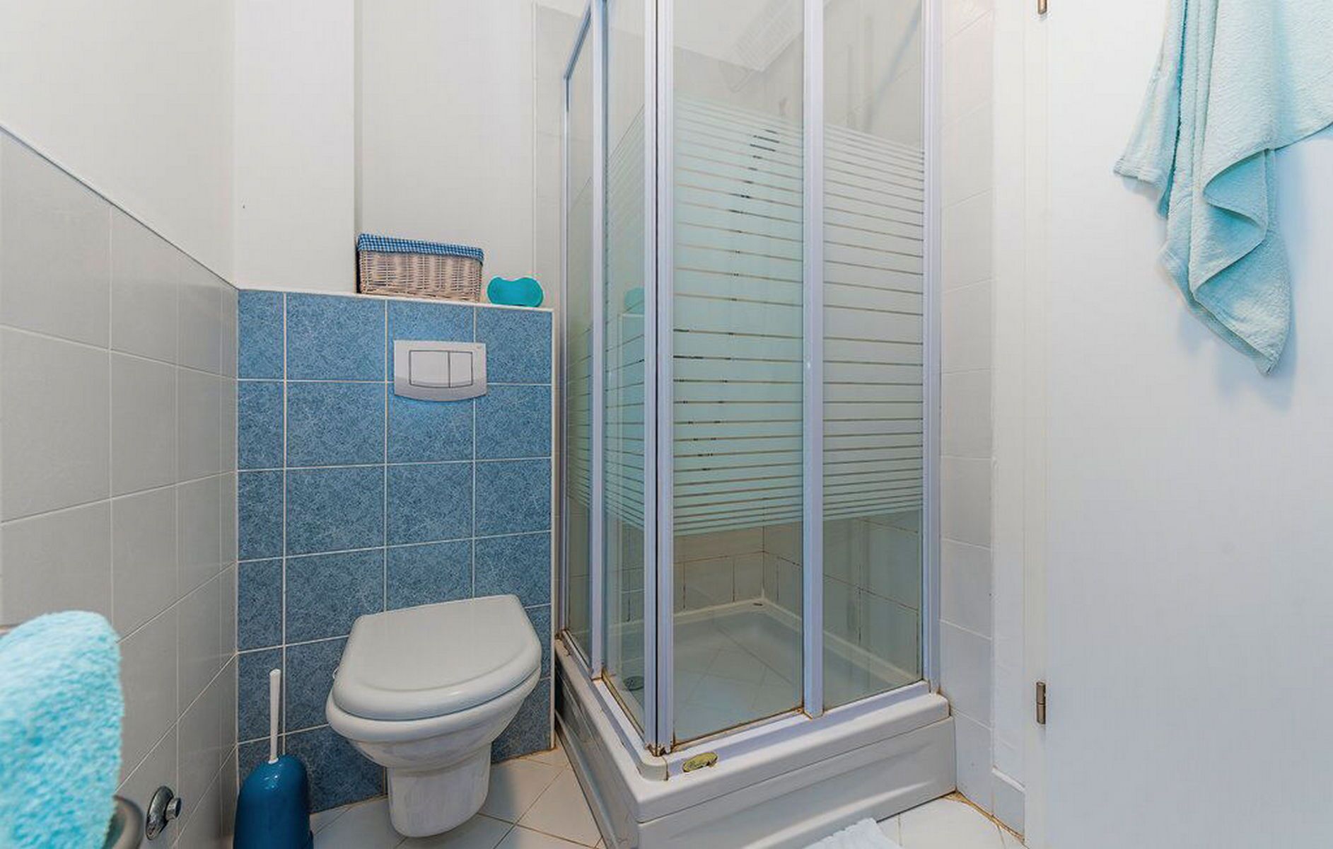 Un baño con inodoro, ducha con puertas de cristal y una toalla colgada en la pared.