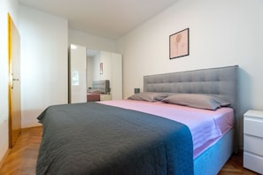 Ein Schlafzimmer mit Bett, Nachttisch, Spiegel und Kleiderschrank.