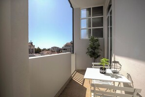 A balcony with a white table and chairs, a potted plant, and a hanging lantern. - Uptown Luxury Flat Boavista With Balcony (Porto)