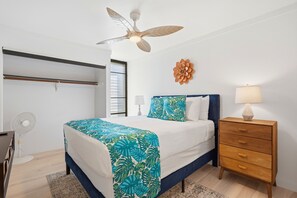 Ein Schlafzimmer mit Bett, Nachttisch und Deckenventilator.