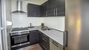A modern kitchen with dark cabinetry, stainless steel appliances, and a built-in oven. - Mobile Home Pen Shell (Biograd na Moru)