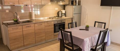 A modern kitchen with wooden cabinets, a stainless steel sink, and a dining area with a table and chairs.