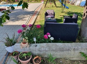 A garden area with outdoor seating, potted plants, and a concrete planter. - Apartments Zeljka B (Rab)