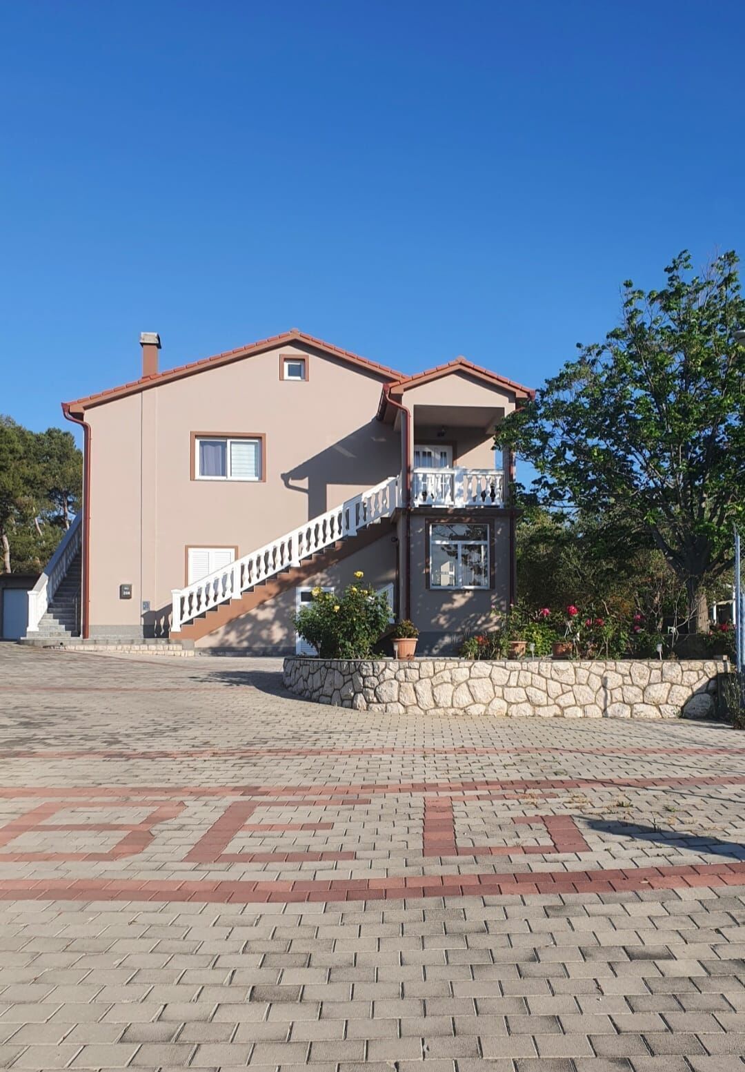 A two-story house with a stone staircase leading to a balcony.