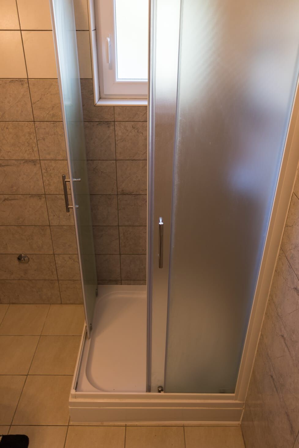 A glass-enclosed shower stall with a white door and a small window above.