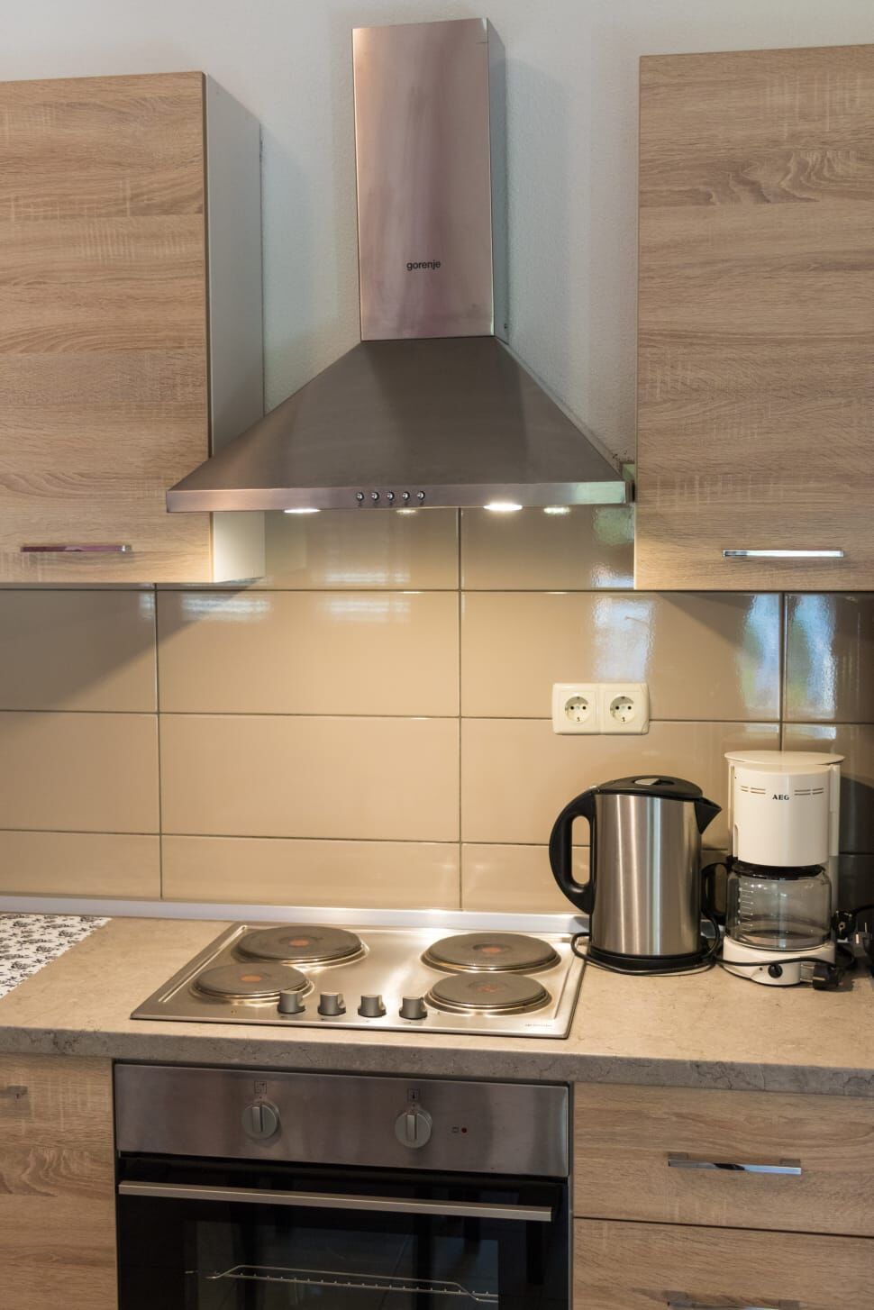A modern kitchen with a stainless steel range hood, a built-in oven, and a coffee maker on the countertop.