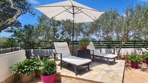 An outdoor patio with two lounge chairs, a table, and a large umbrella. - House Relaxing Oasis (Stari Grad)