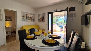 A dining area with a table set for four, a yellow sofa, and artwork on the walls. - House Relaxing Oasis (Stari Grad)