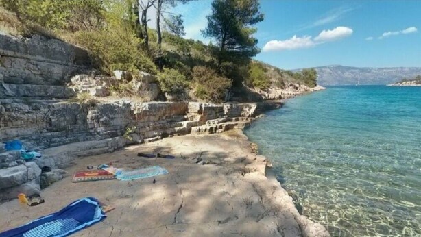 A rocky shoreline with clear water, a towel, and a small rug on the ground. - House Relaxing Oasis (Stari Grad)