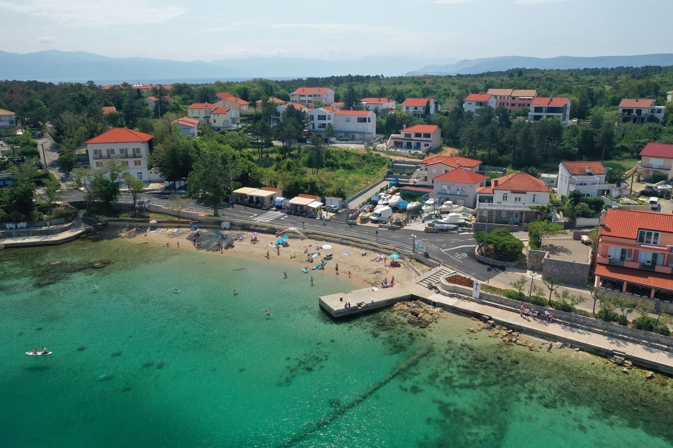 An aerial view of a coastal town with buildings, a beach, and a pier.