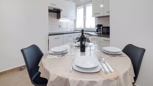 Una cucina moderna con mobili bianchi, un tavolo da pranzo apparecchiato con piatti, bicchieri e posate.