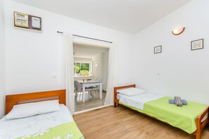 A room with two beds, a dining table, and a view through an open door. - Apartment Close to the Beach (Stari Grad)
