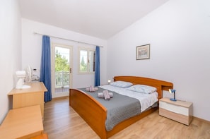 A bedroom with a bed, bedside table, nightstand, and a fan. - Apartment Close to the Beach (Stari Grad)