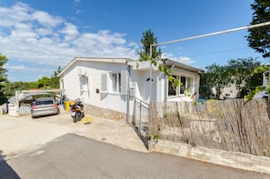 A residential building with a garage, parked car, and motorcycle. - Apartment Close to the Beach (Stari Grad)