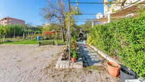 Ein Gartenweg mit Blumentöpfen, einer Bank und einer Pergola.
