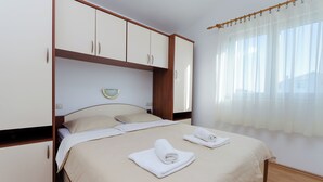 Ein Schlafzimmer mit Bett, zwei Handtüchern, einem Nachttisch, einem Spiegel und einem Kleiderschrank.