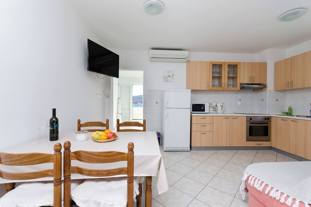 A modern kitchen with wooden cabinets, a built-in microwave, and a refrigerator.