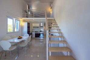 Eine moderne Küche mit Essbereich, einer Treppe und Blick ins Freie.