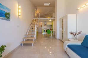 Ein modernes Interieur mit einer Treppe zu einem Schlafbereich, einem Essbereich und einem Wohnbereich mit einer Couch und einem kleinen Tisch.