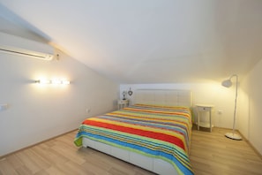 Ein Schlafzimmer mit Bett, Nachttischen, einer Stehlampe und einer Klimaanlage.