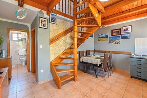 A wooden staircase in a home with a dining area and kitchen. - House Silvijo (Pag)