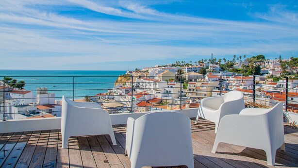 Een terras met witte stoelen met uitzicht op een kustplaats.