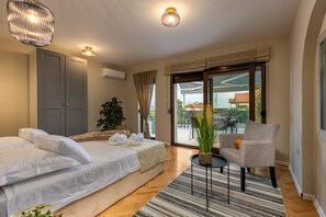 Quarto de hotel com cama, uma cadeira, uma mesa pequena e vista para o exterior.