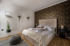 A neatly arranged bedroom with a large bed, bedside tables, and a wall-mounted mirror. - Apartment Vila Ninna (Opatija)