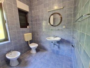 A bathroom with two toilets, a sink, and a mirror. - Apartments Vukelic (Crikvenica)