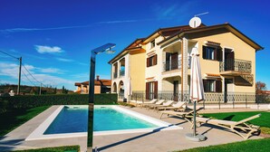 A two-story house with a swimming pool, outdoor furniture, and a well-maintained lawn. - Apartment Istria (Vizinada)