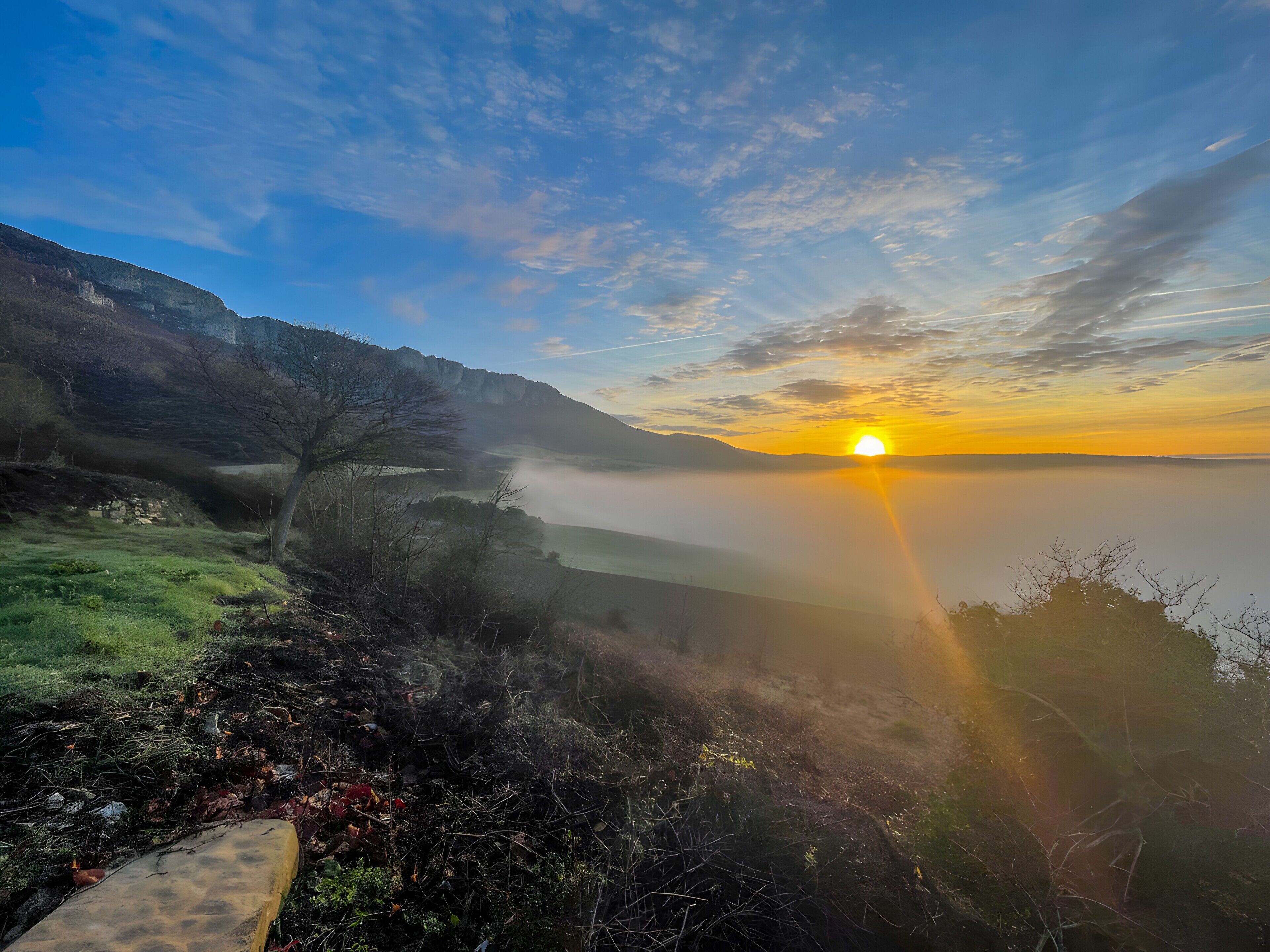Un amanecer sobre un valle con cielo despejado y una montaña distante.