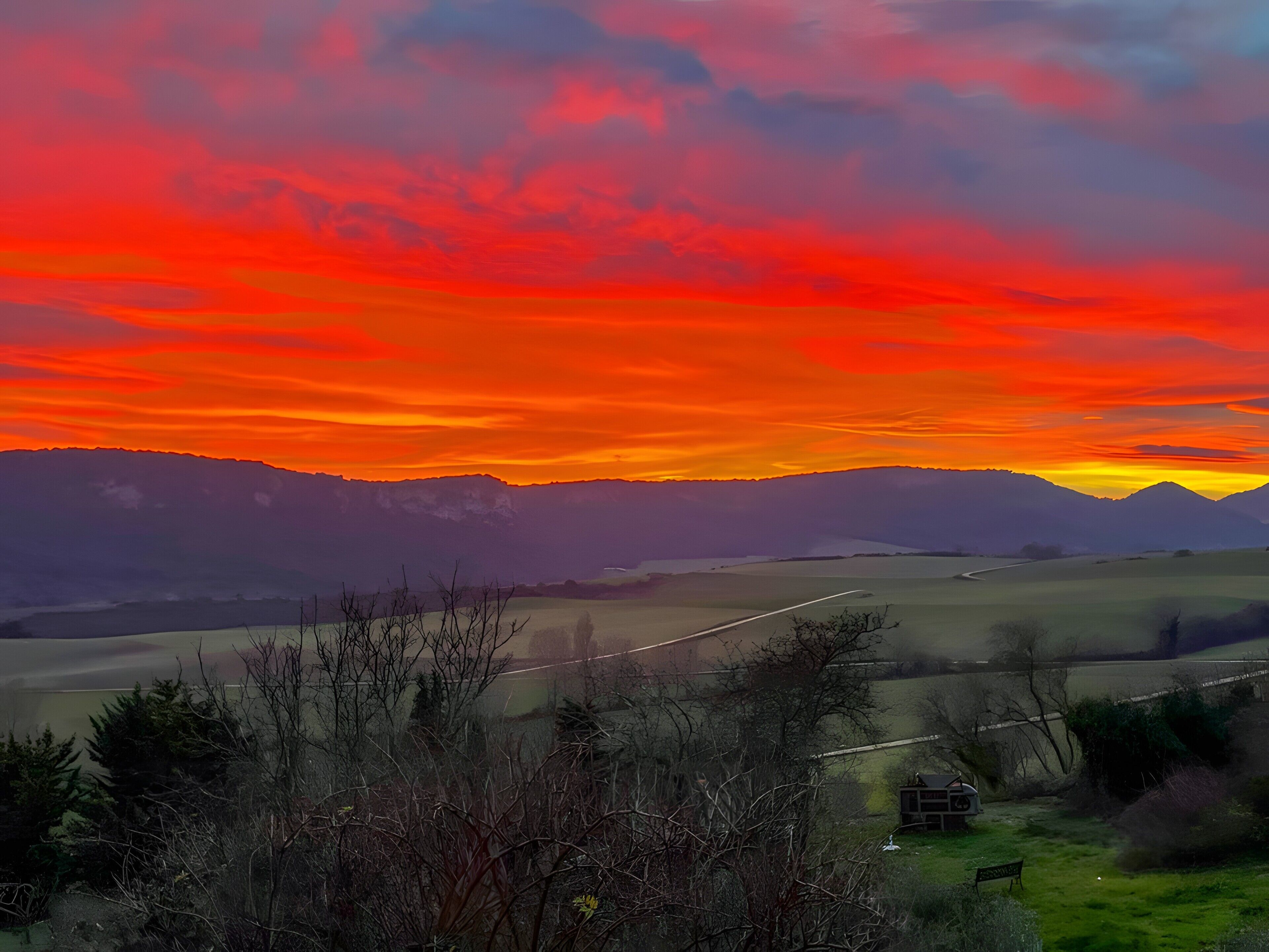 Un paisaje con una carretera, montañas y un atardecer.