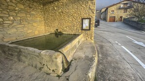 Un edificio de piedra con muro de piedra, una pequeña piscina y techo de madera.
