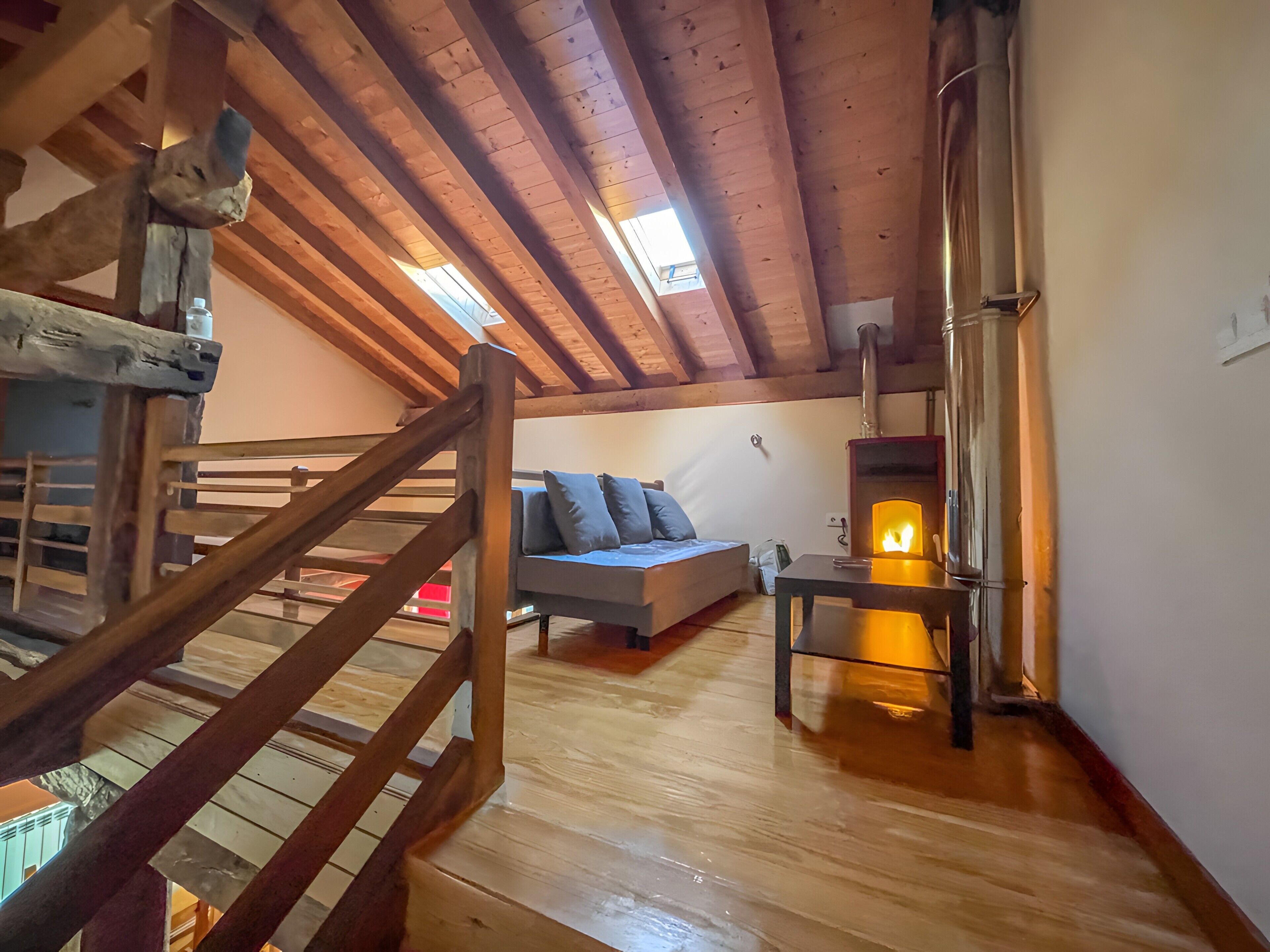 Ein Schlafzimmer im Landhausstil mit einer Schlafterrasse, einer Couch, einem Tisch und einem Kaminofen.