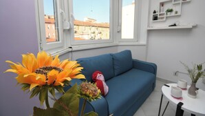 A room with a blue sofa, a small table with cups, a potted plant, and a large sunflower. - Apartment Corina (Rijeka)