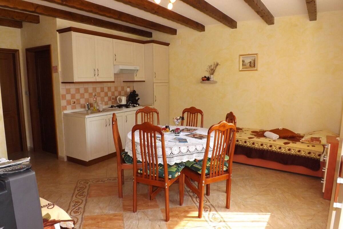 A cozy room with a dining table, chairs, a bed, and a kitchenette.