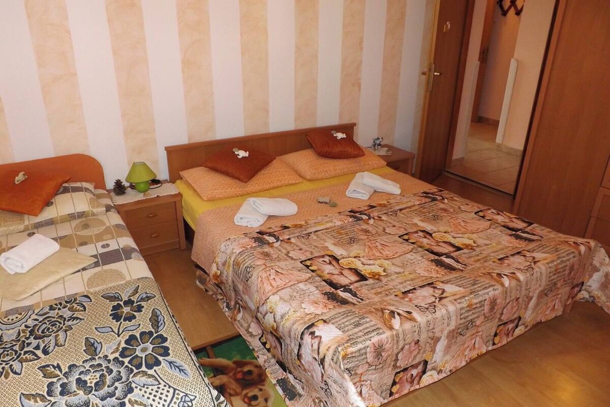 A bedroom with two beds, a wooden wardrobe, and a mirror.