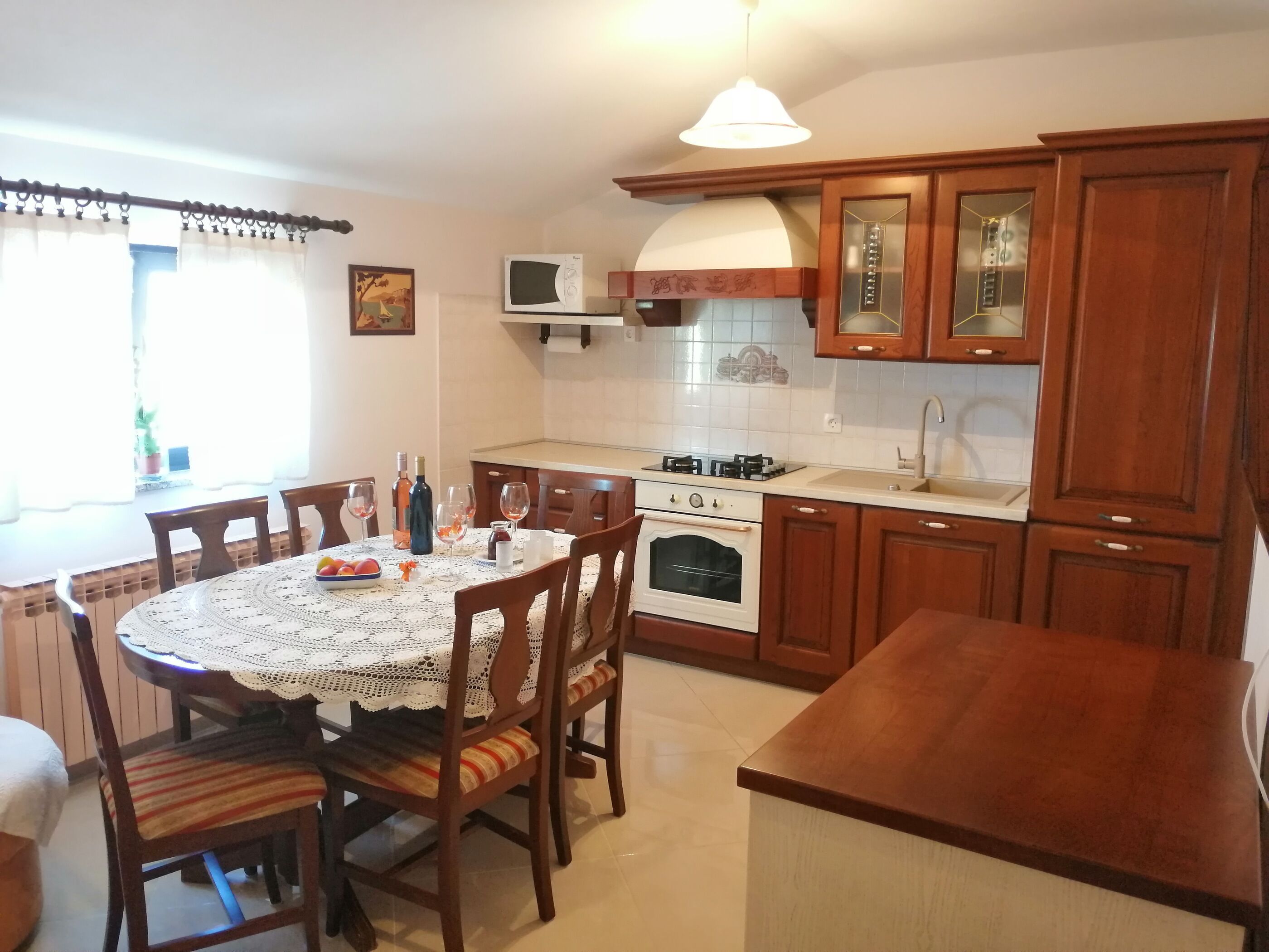A kitchen with wooden cabinets, a stove, microwave, and a dining table with chairs.