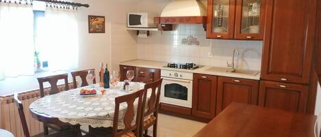 A kitchen with wooden cabinets, a stove, microwave, and a dining table with chairs.