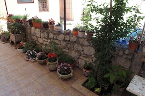 A stone wall with potted plants and flowers arranged along it. - Apartments Valter (Umag)