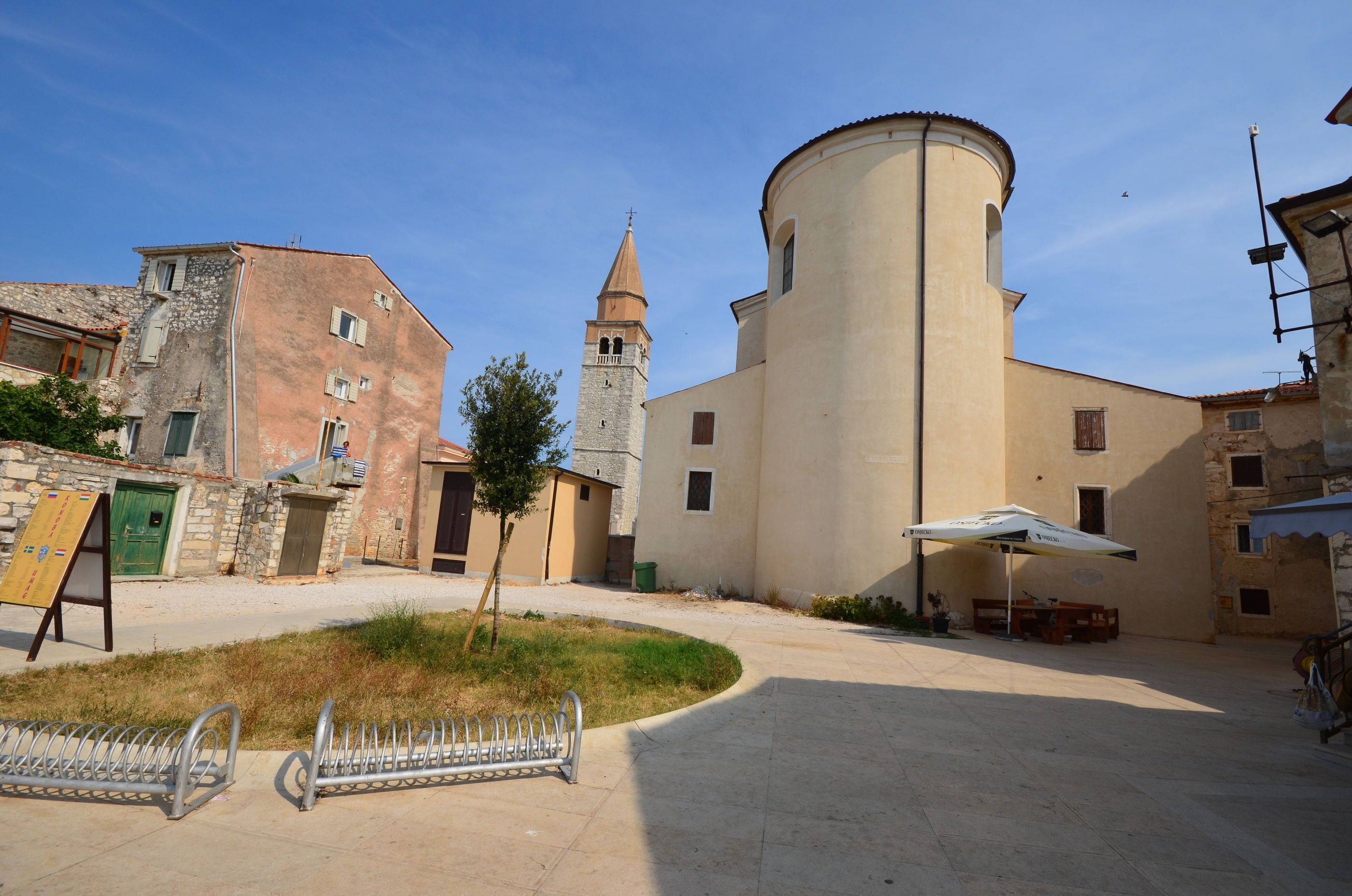 A courtyard with a stone building, a tower, and a large cylindrical structure.